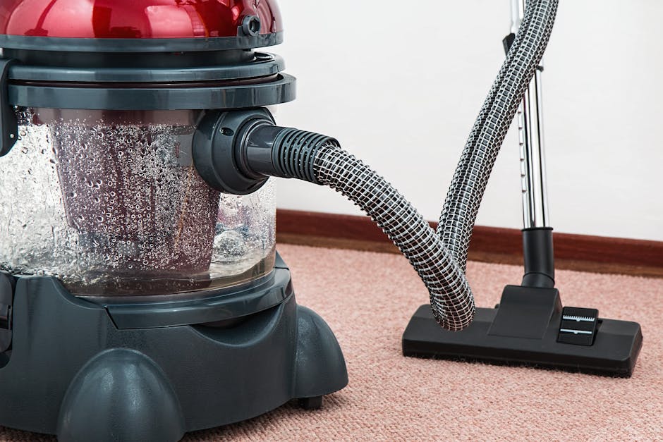 Three professional cleaners from Richmond upon Thames Carpet Cleaners stand in a modern living room, equipped with various cleaning tools including a vacuum cleaner, a mop, and a spray bottle. The roo